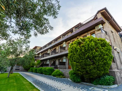 Assos Park Hotel bahçesi ve ahşap balkonlu bina cephesi
